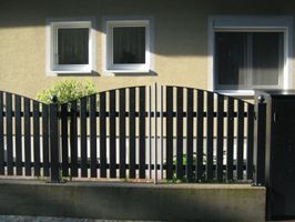 Dunkler Zaun mit hellen Latten dazwischen in der Mitte
