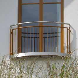 leicht gebogenes Geländer vor Balkonfenster an der Außenwand