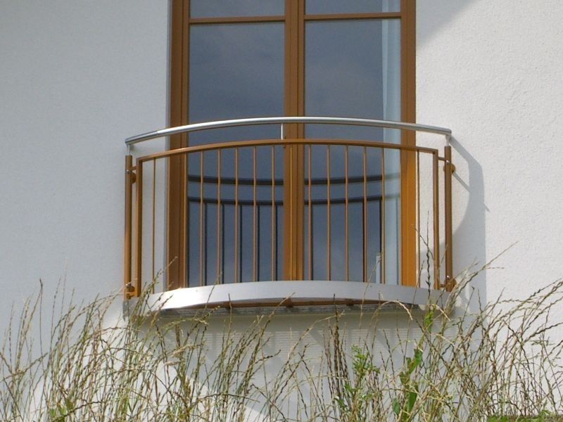 leicht gebogenes Geländer vor Balkonfenster an der Außenwand