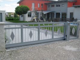 hellgraues großes Einfahrtstor mit Karo-Elementen auf den Stangen