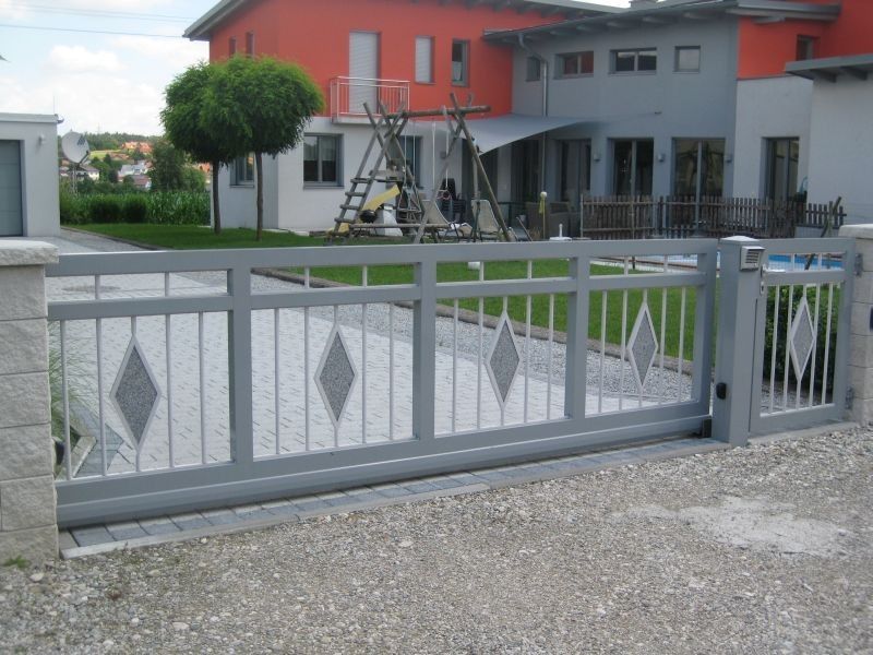 hellgraues großes Einfahrtstor mit Karo-Elementen auf den Stangen